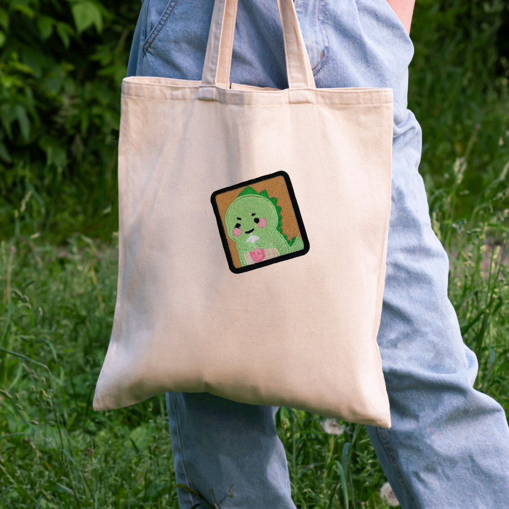 Tote bag with a cartoon character patch held by a person in an outdoor setting