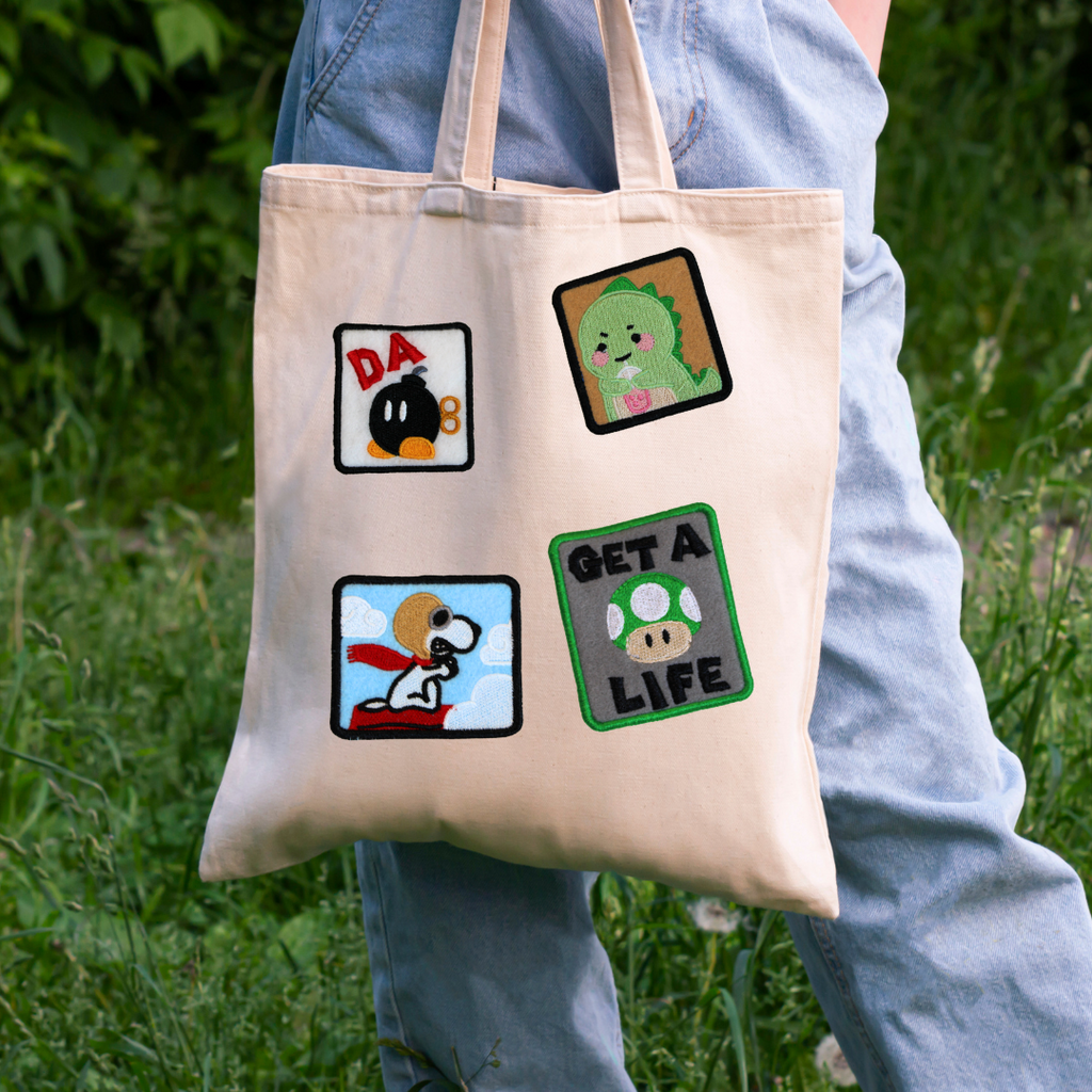 Tote bag with cartoon character designs held by a person outdoors.