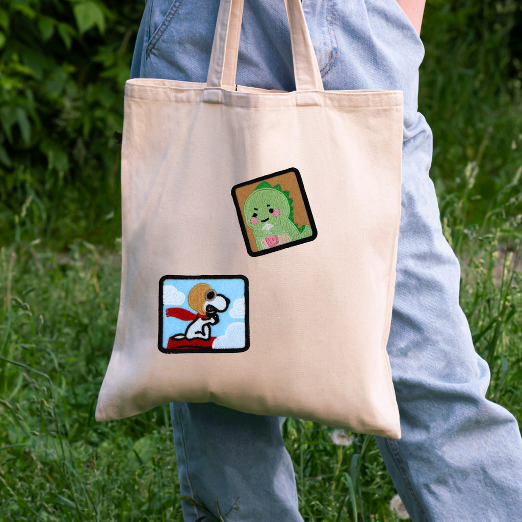Tote bag with cartoon designs held by a person in a natural setting