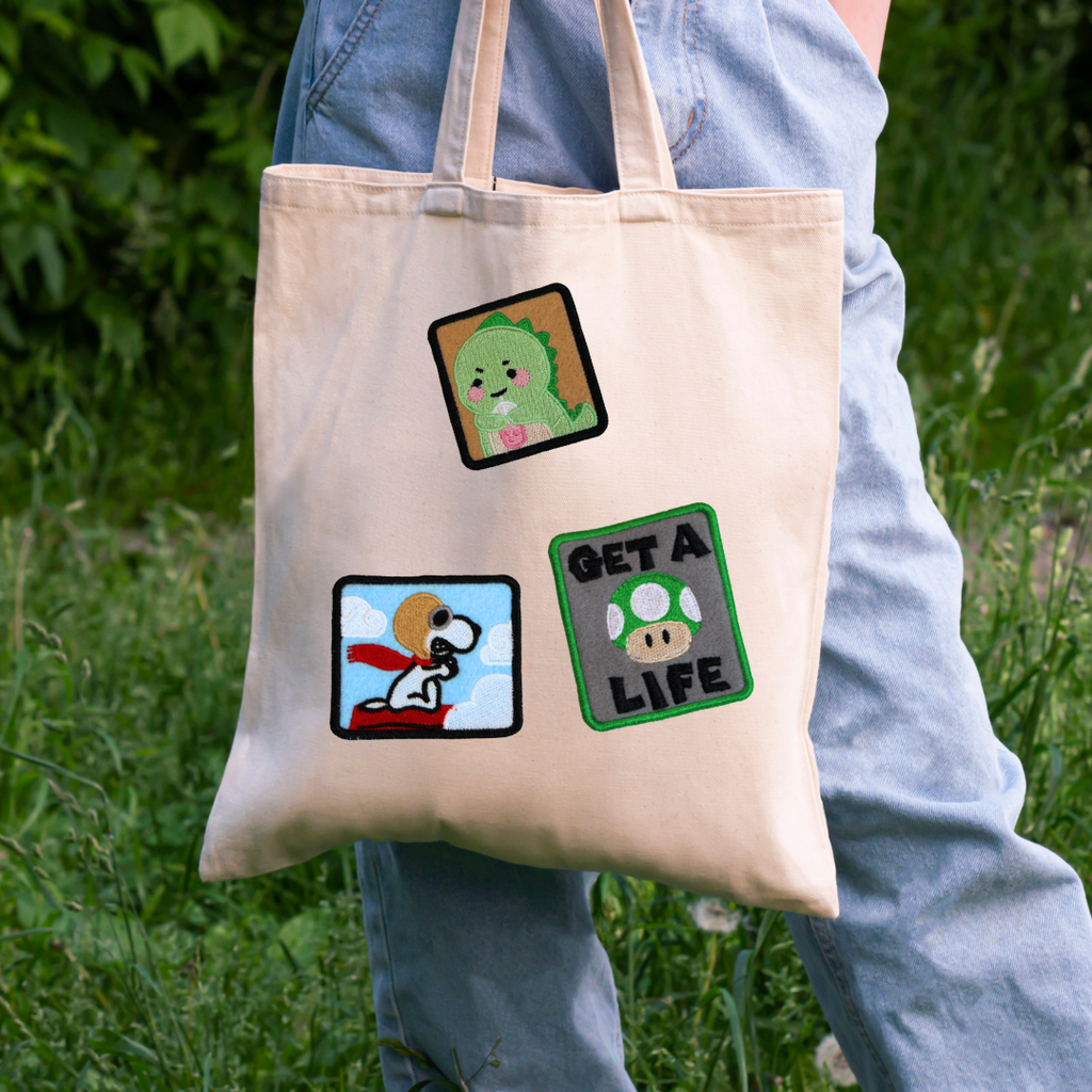 Tote bag with cartoon character designs held by a person outdoors.