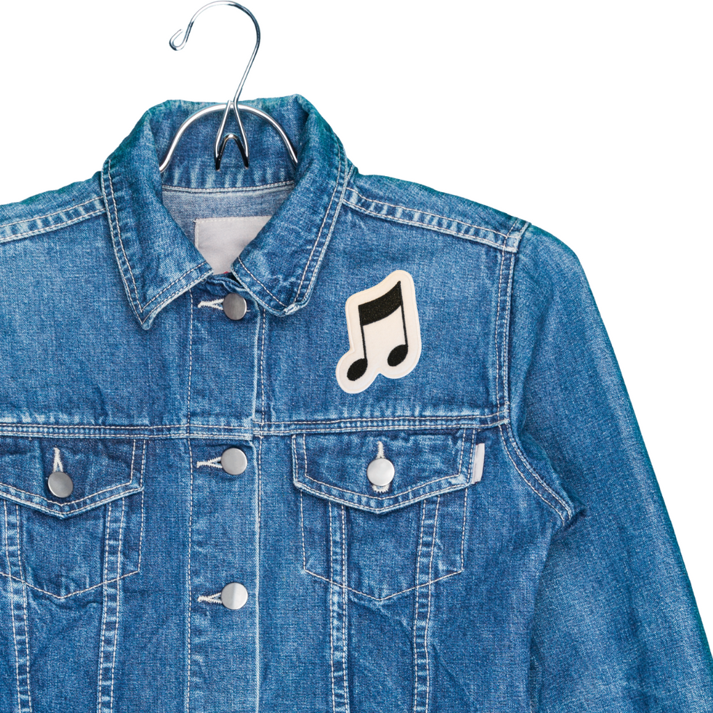 Blue denim jacket with a music note patch on a white background