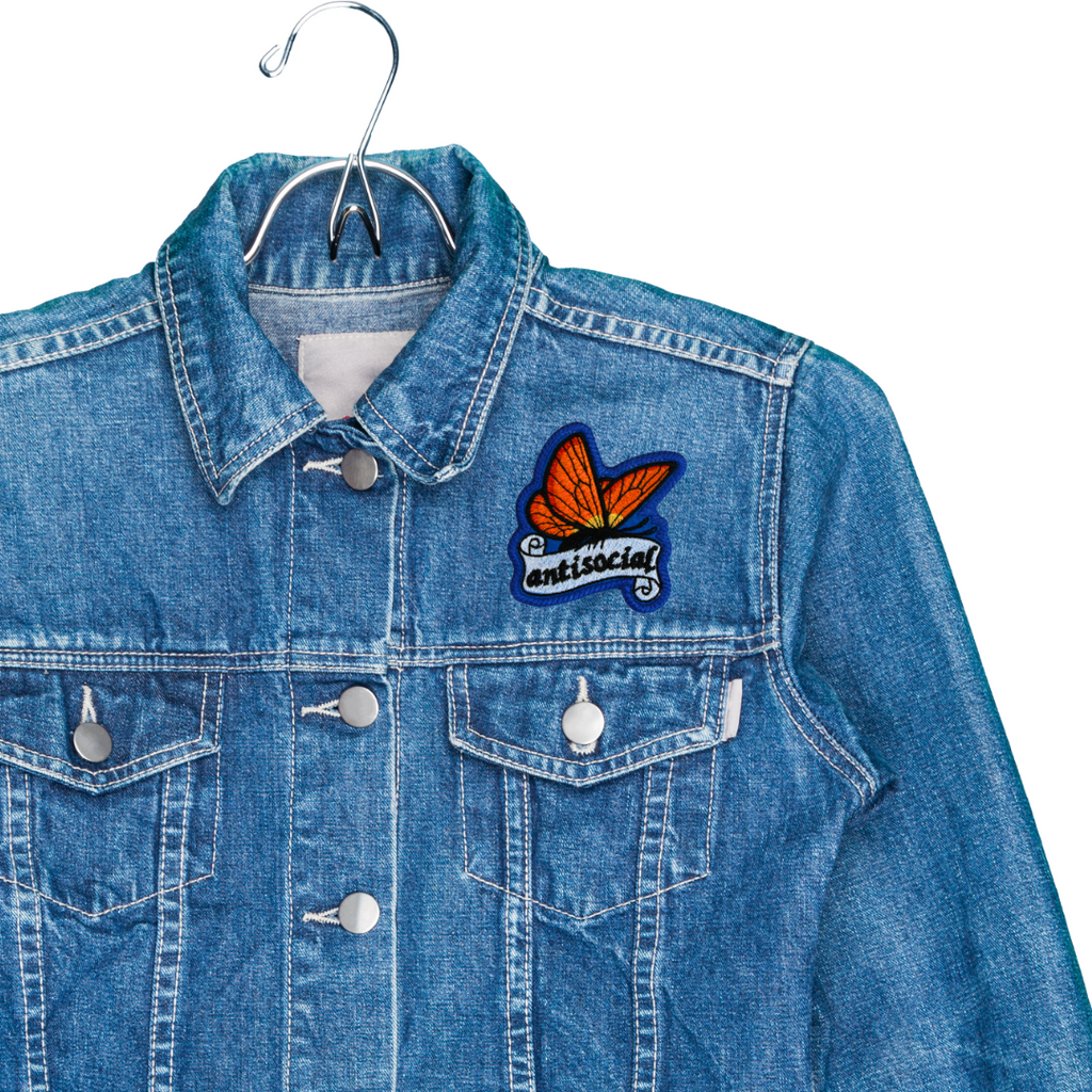 Blue denim jacket with a butterfly patch on a hanger