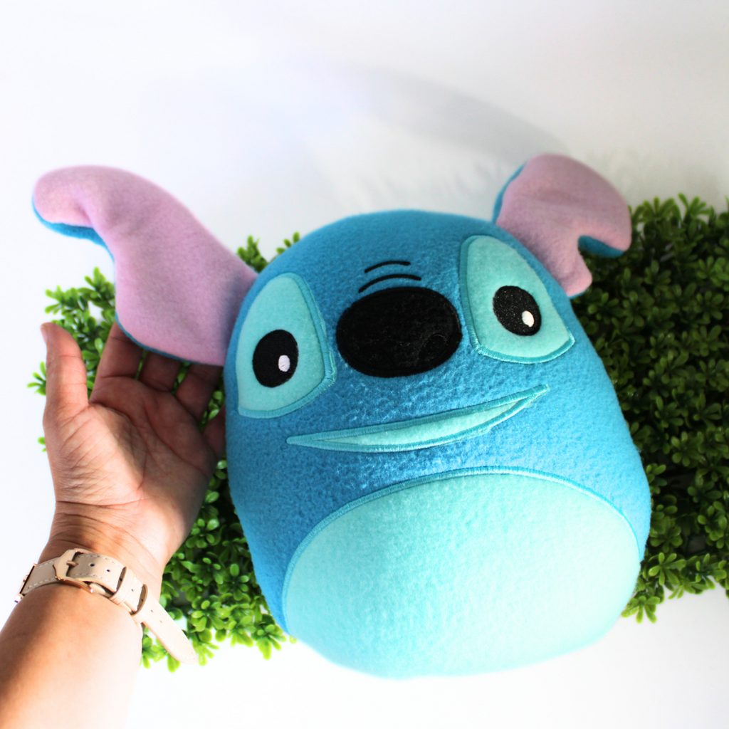 Plush toy resembling a character with a blue face and pink ears on a white background