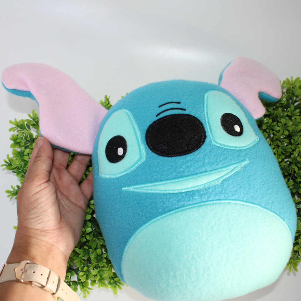 Plush toy resembling a character with a blue face and pink ears on a white background