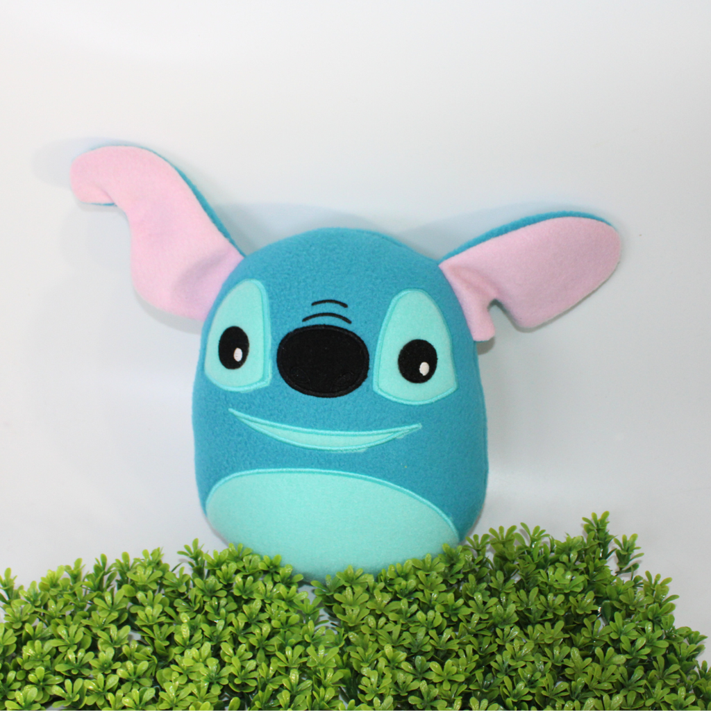 Plush toy resembling a character with a blue face and pink ears on a white background