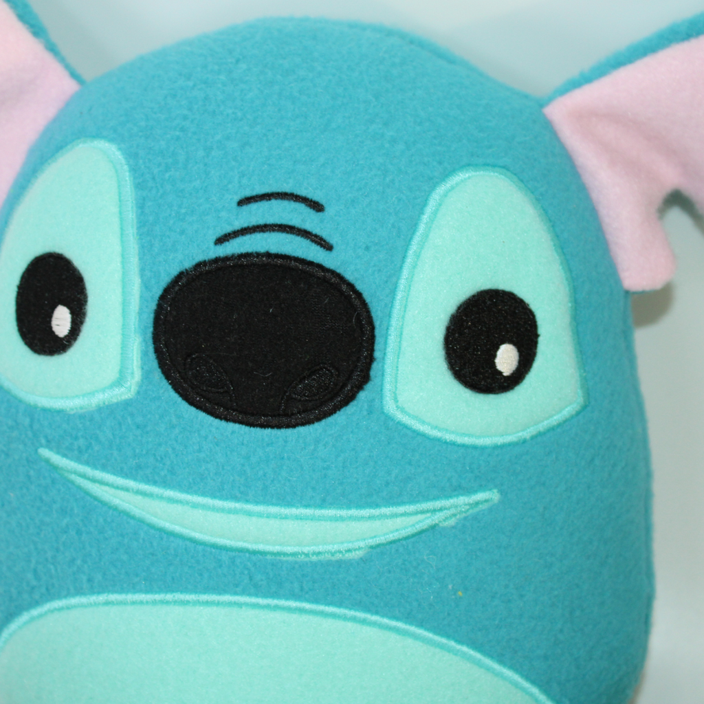 Plush toy resembling a character with a blue face and pink ears on a white background