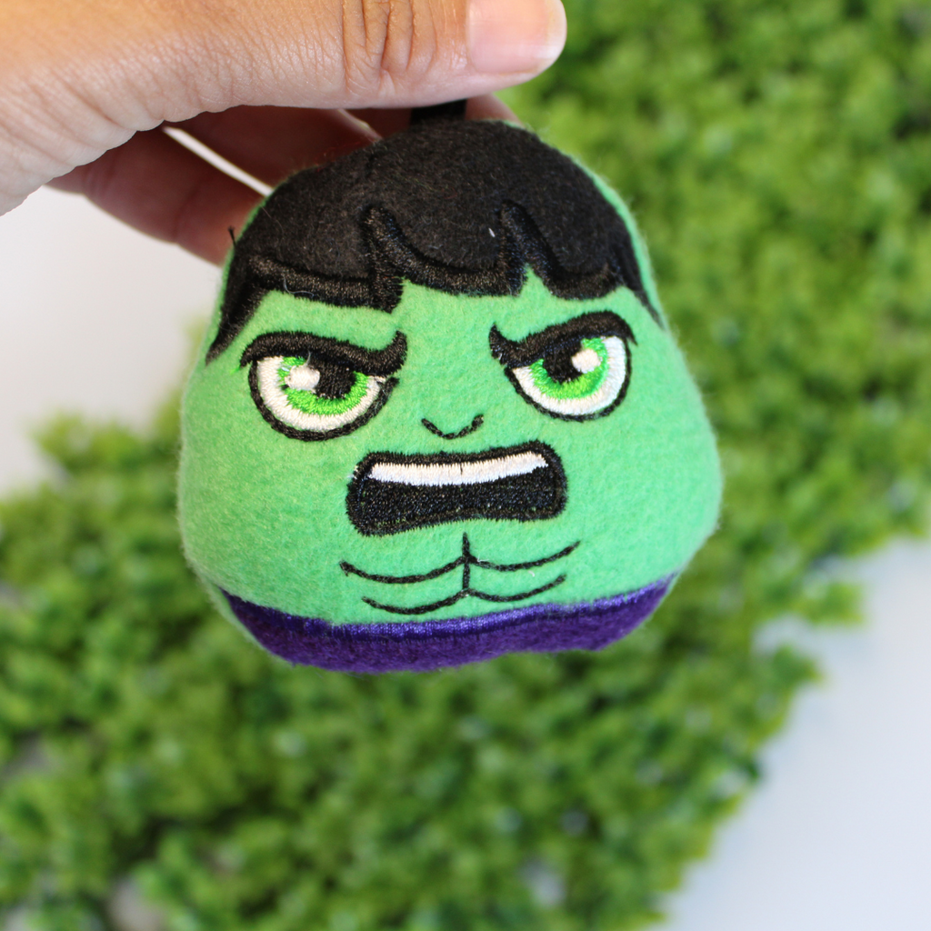Green plush toy resembling a superhero with a textured green background