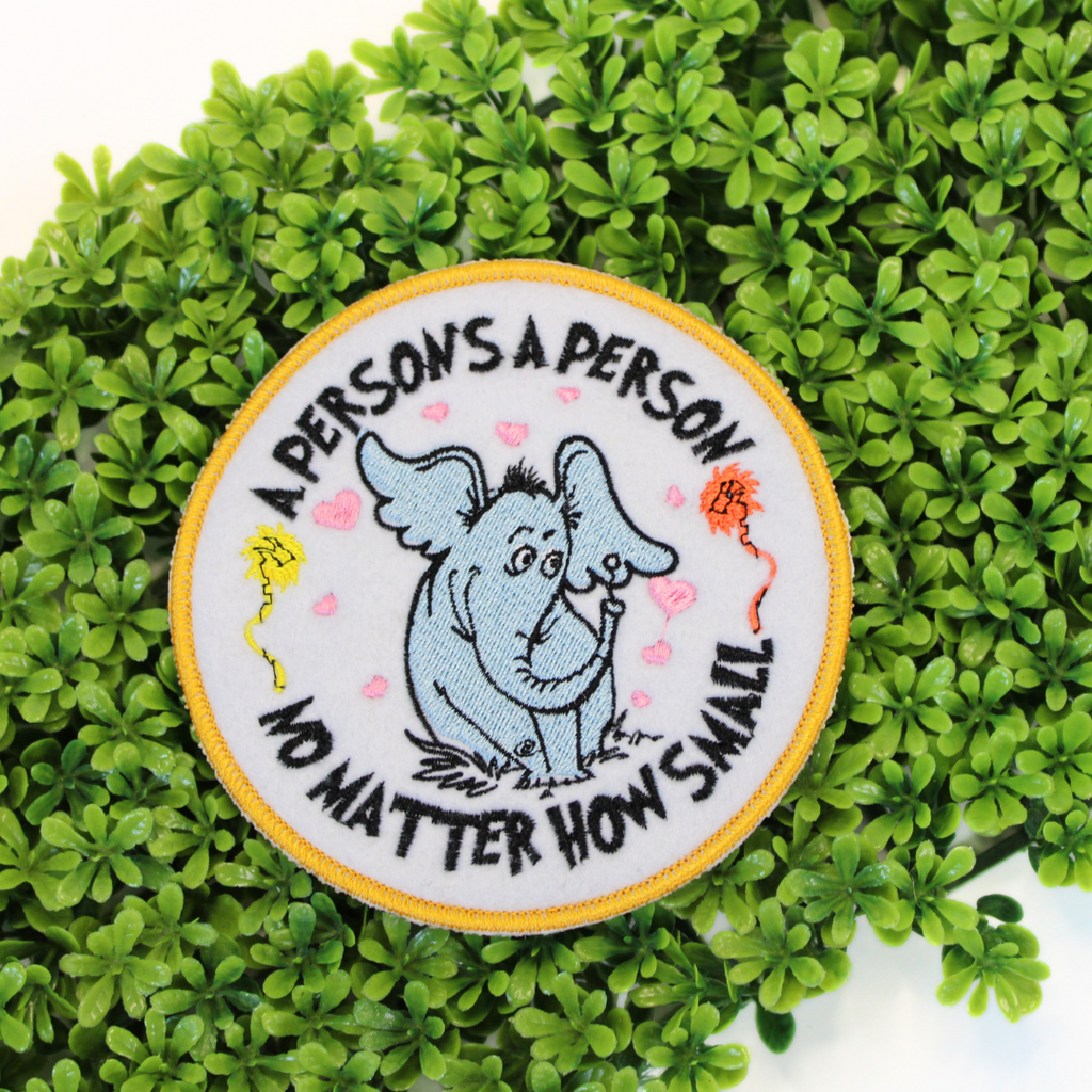 Patch with an elephant illustration and text on a green leaf background