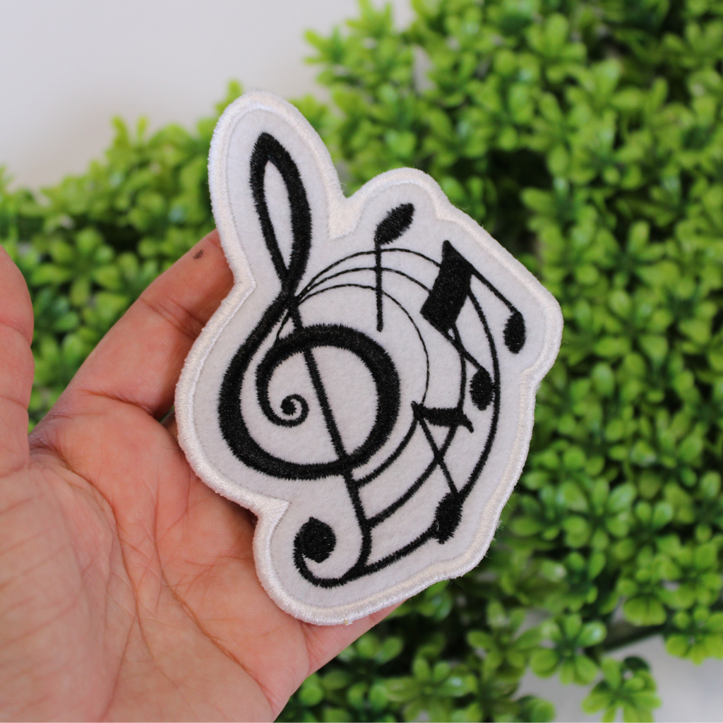 Patch with musical notes held in front of green foliage