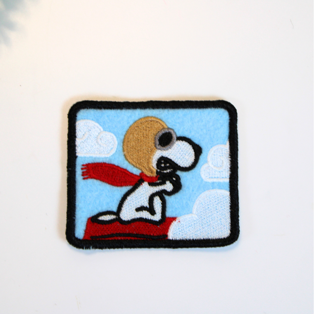 Embroidered patch of a dog with a red scarf on a blue background