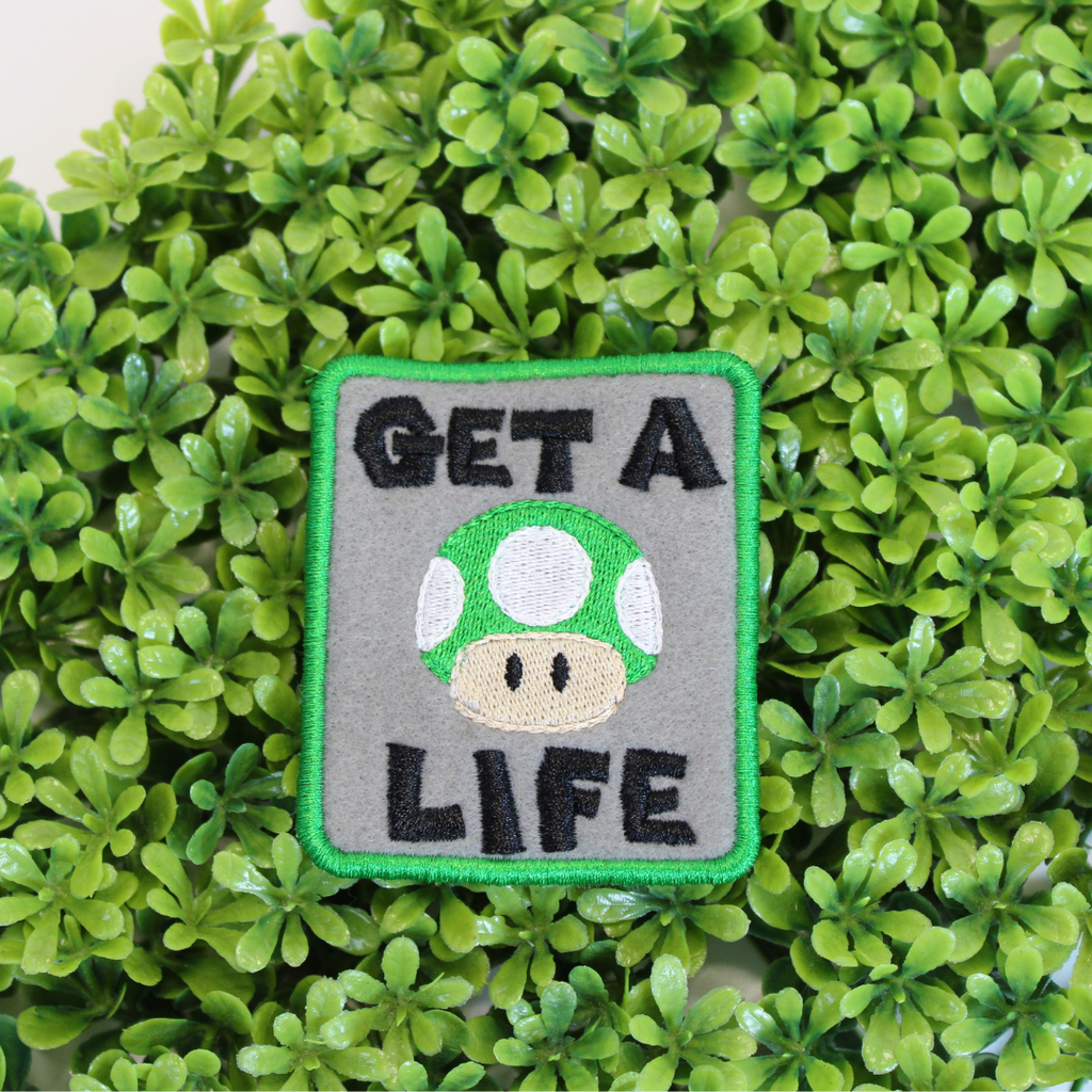 Patch with mushroom design and 'GET A LIFE' text on a green leaf background