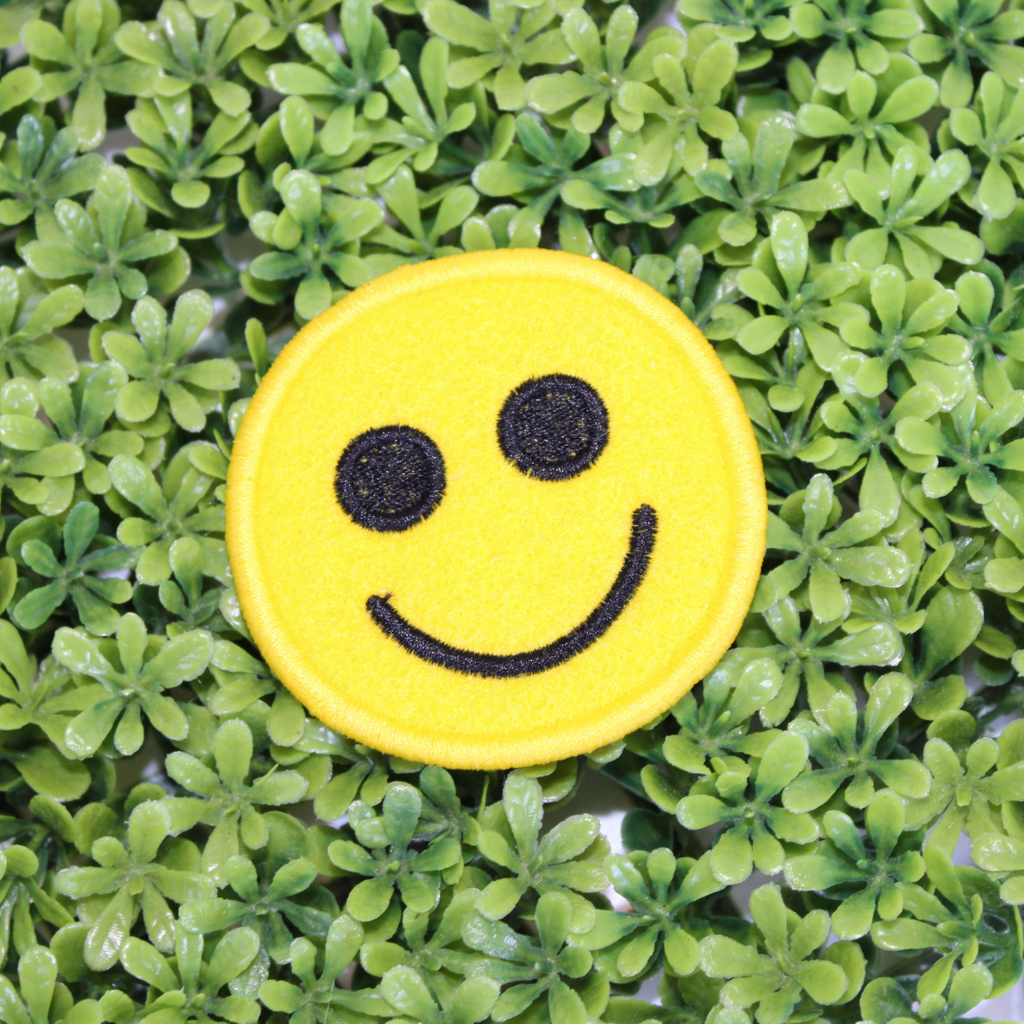 Yellow smiley face patch on a green leaf background