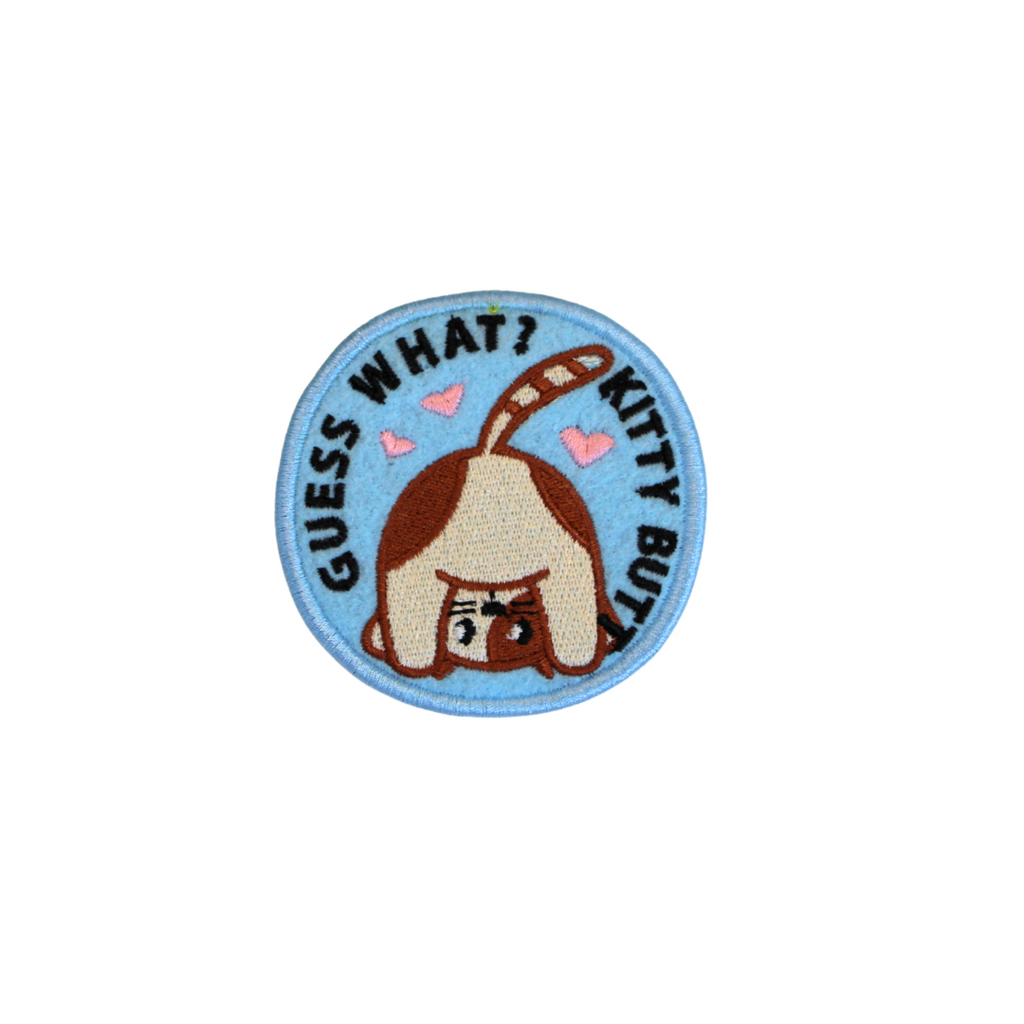 Circular patch with a cat illustration and text 'Guess What? Kitty Butt' on a white background