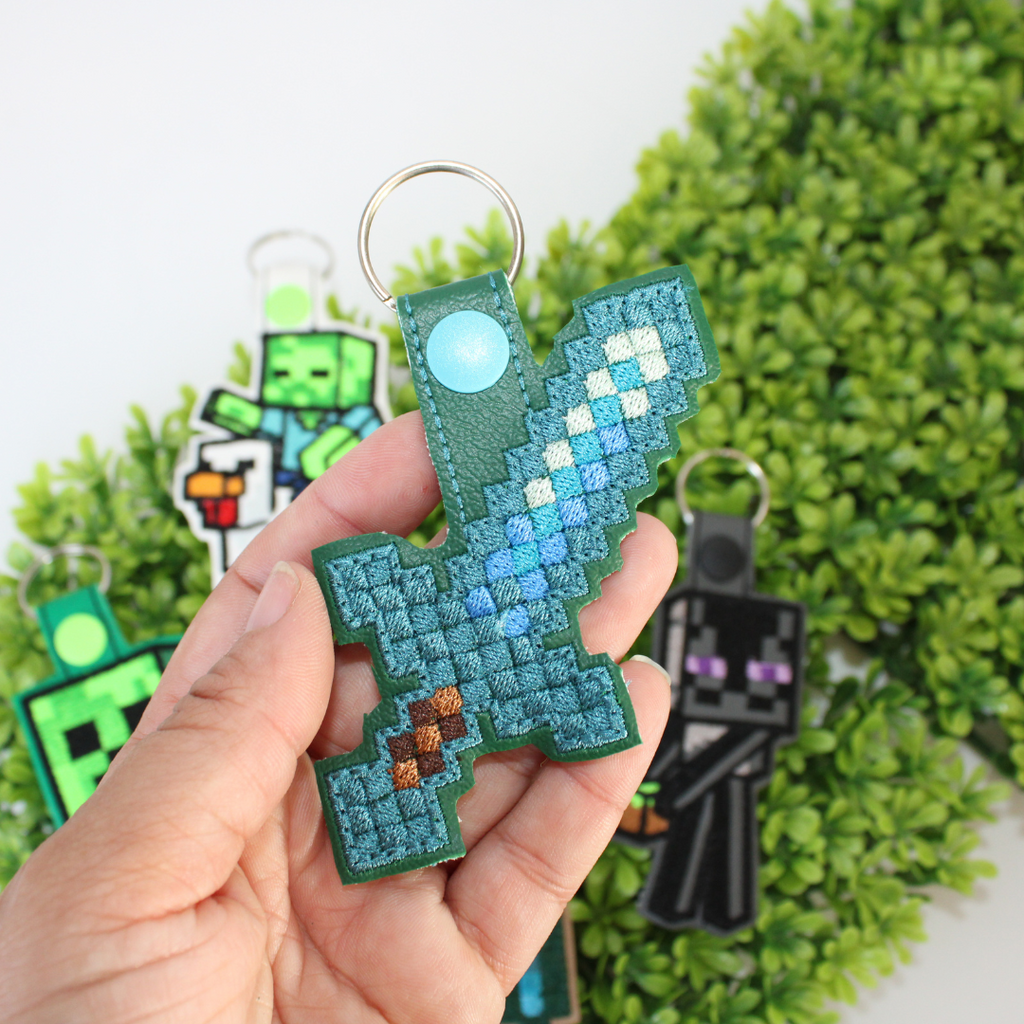 Set of Minecraft-themed keychains on a green leaf background