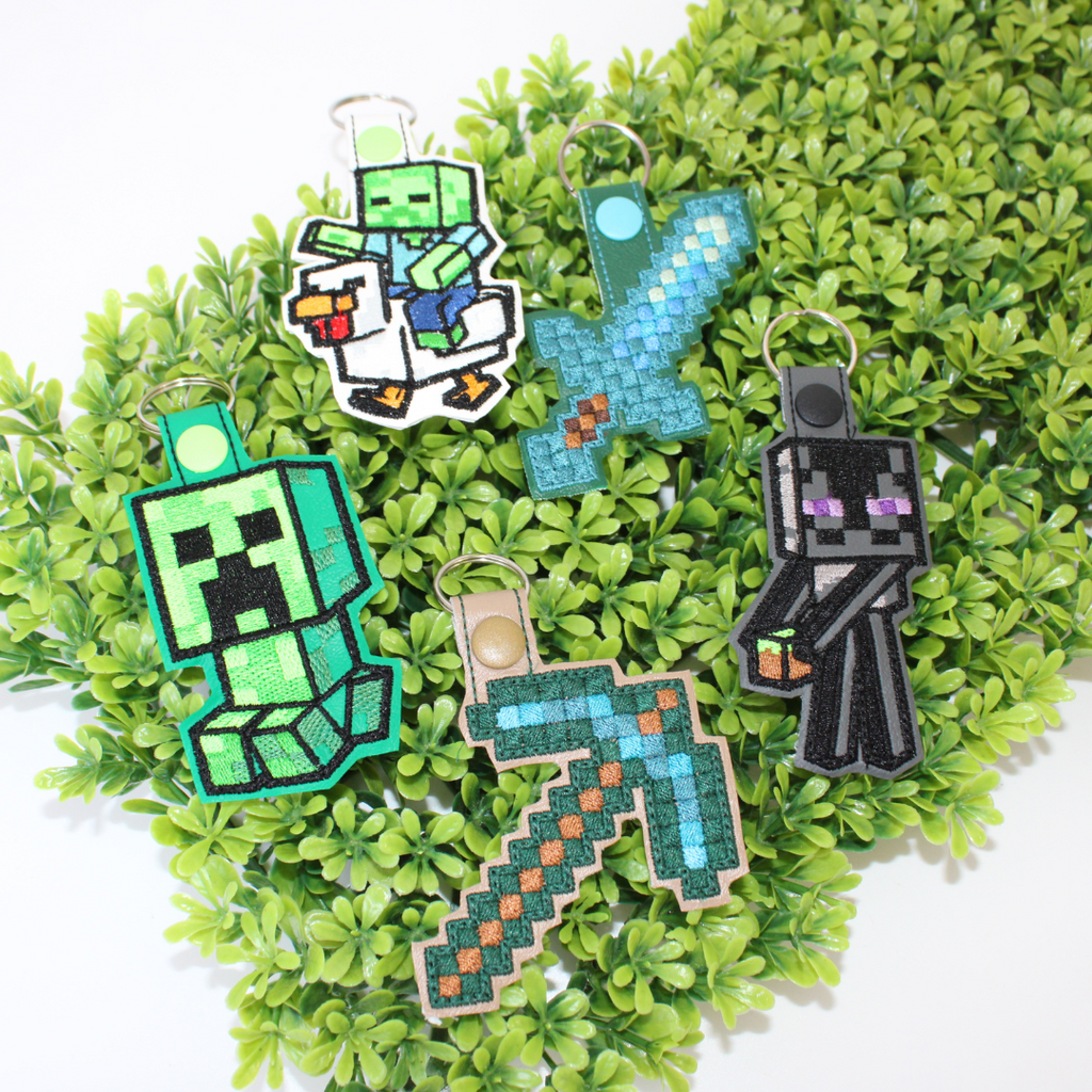 Set of Minecraft-themed keychains on a green leaf background