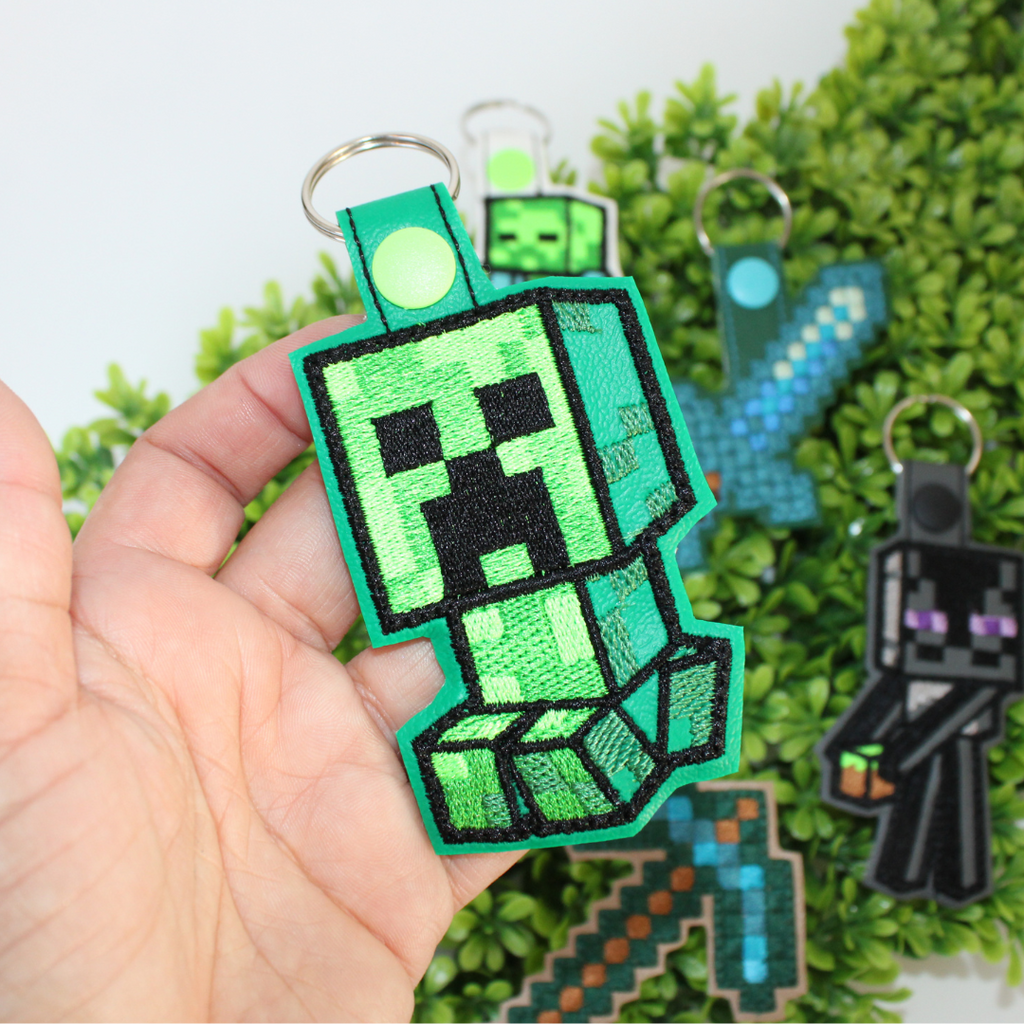 Set of Minecraft-themed keychains on a green leaf background