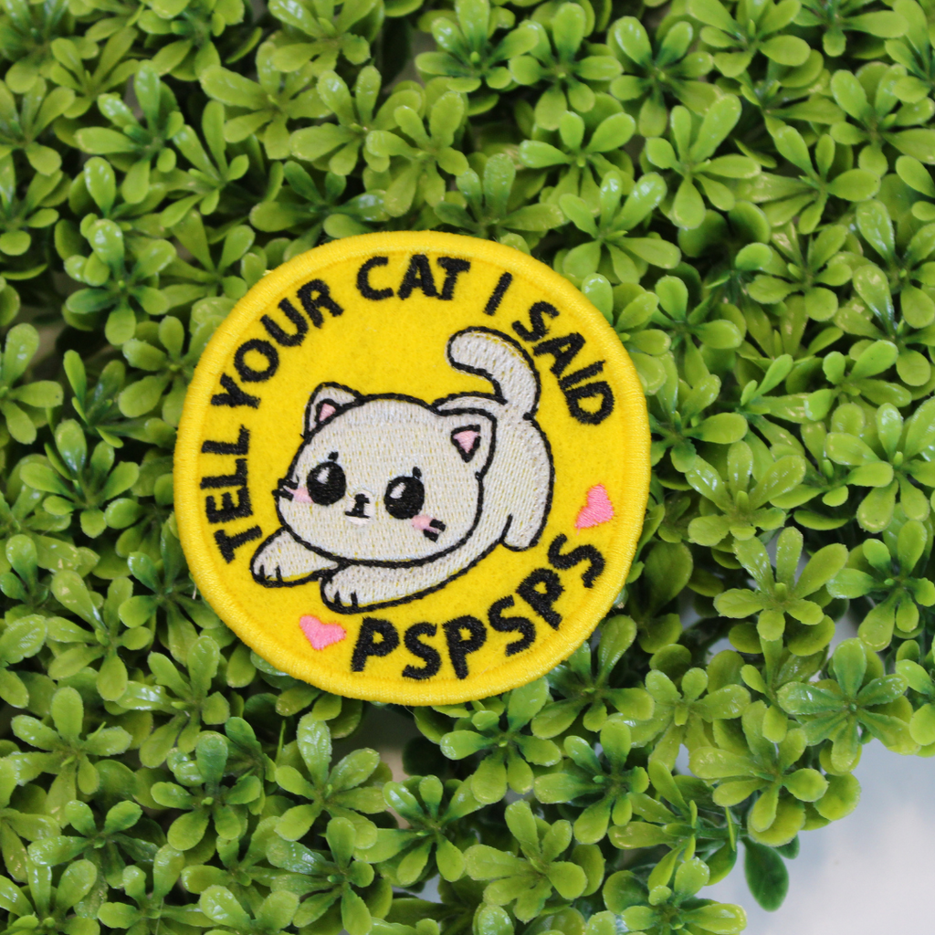 Patch with a cartoon cat and text on a green leaf background